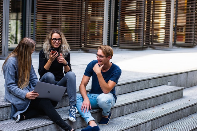 one boy and two girls sitting on stairs with a laptop