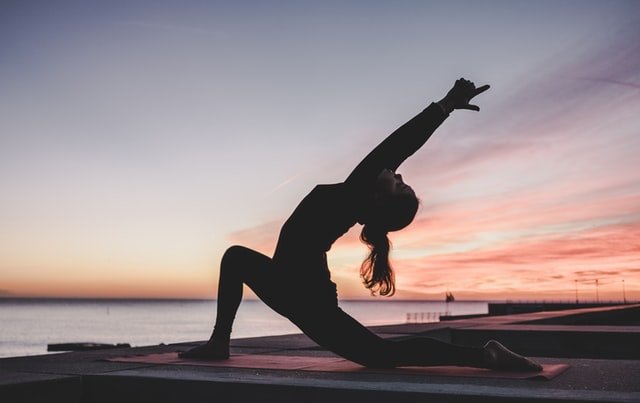 a lady doing yoga near a sunset point