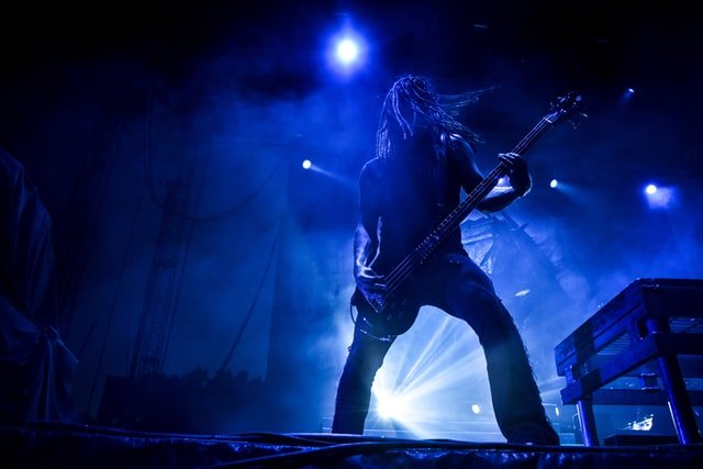 Rockstar playing guitar under blue lights on a stage