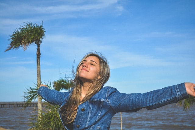 A girl standing with her arms open and eyes closed