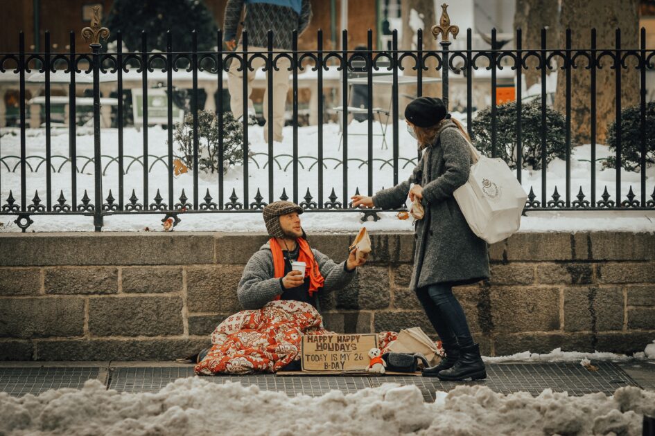 a lady helping a homeless man