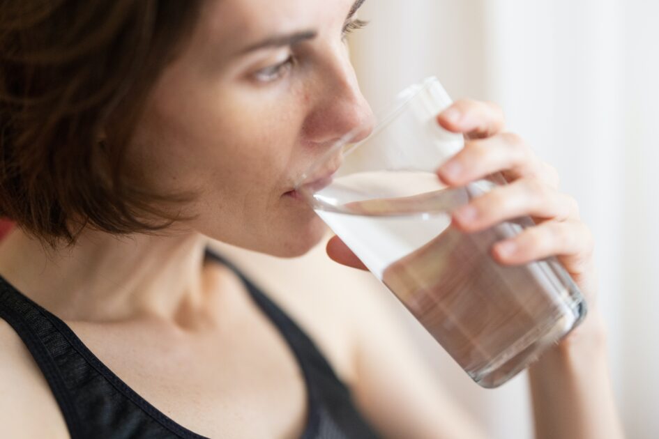 a short haired white woman drinking a glass of water