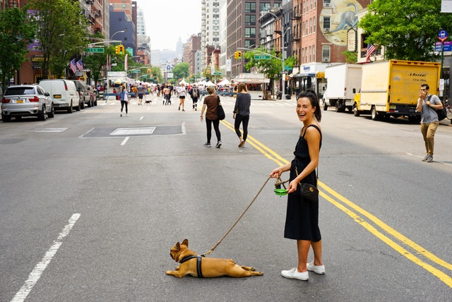 dog lying on road with a lady smiling