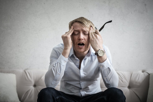 A guy feeling anxious sitting on a couch.