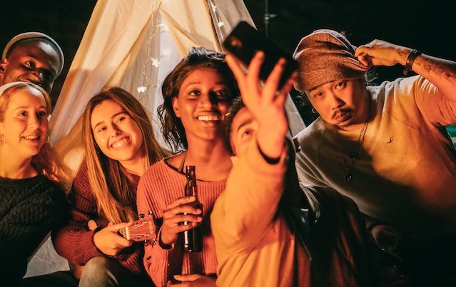 Group of people taking selfie outside a camp at night.