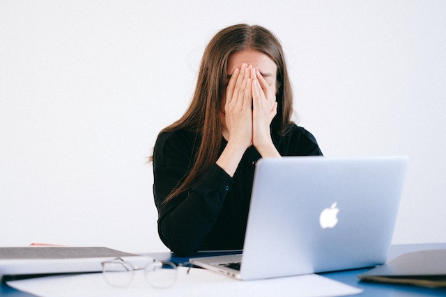 A women suffering from anxiety sitting with a macbook.